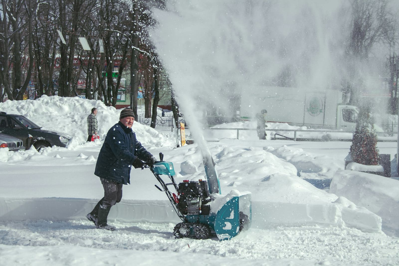Lumilinko heittää lunta omakotitalon pihatiellä lumisateen jälkeen